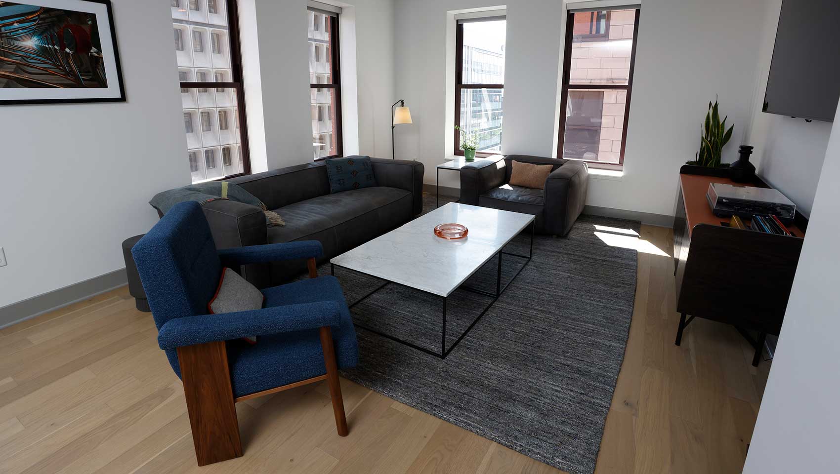 Levi Level Rockefeller Suite sitting area with couch, chairs, coffee table, TV and natural light from windows