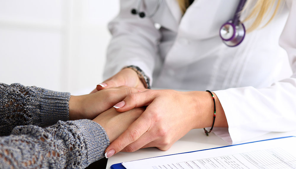 Close up of a doctor holding a patients hands